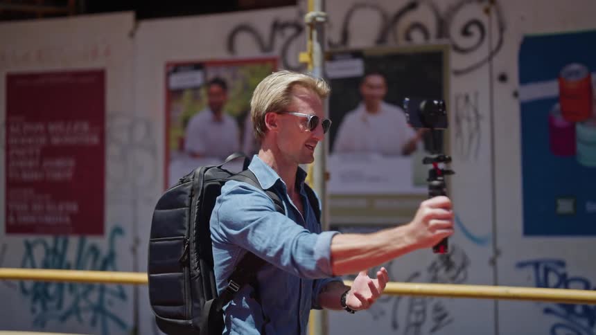 A man walking around and smiling while using a smartphone to film things around him