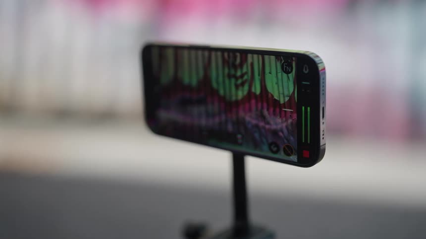 A person is holding a smartphone with a special handle and adjusting the app settings to use it as a camera