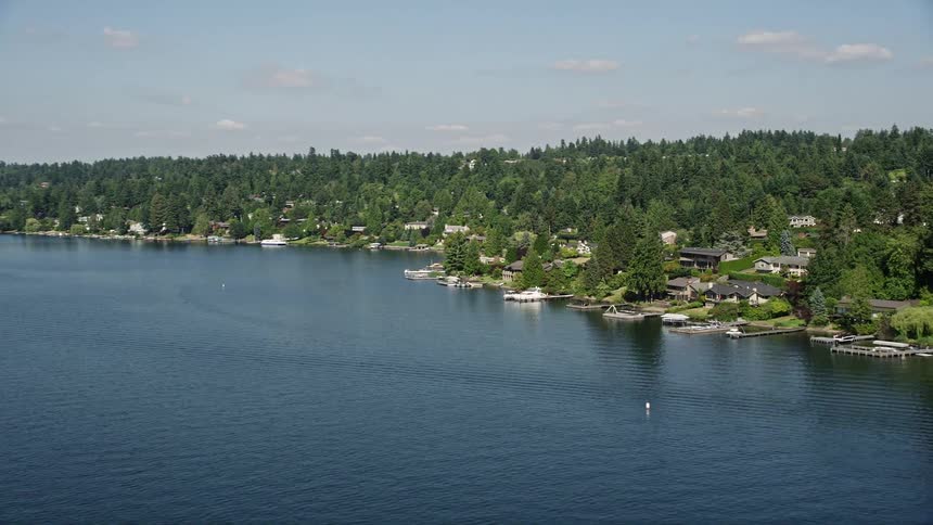 A sunny aerial view of lakeside homes with docks in Mercer Island Washington showcasing the picturesque waterfront and residential neighborhood