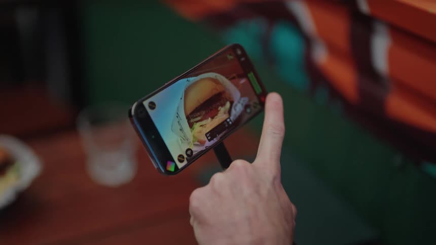 A man records video of his burger in a restaurant