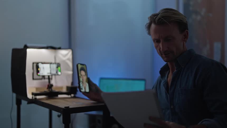 A man takes a video call while recording video on another phone