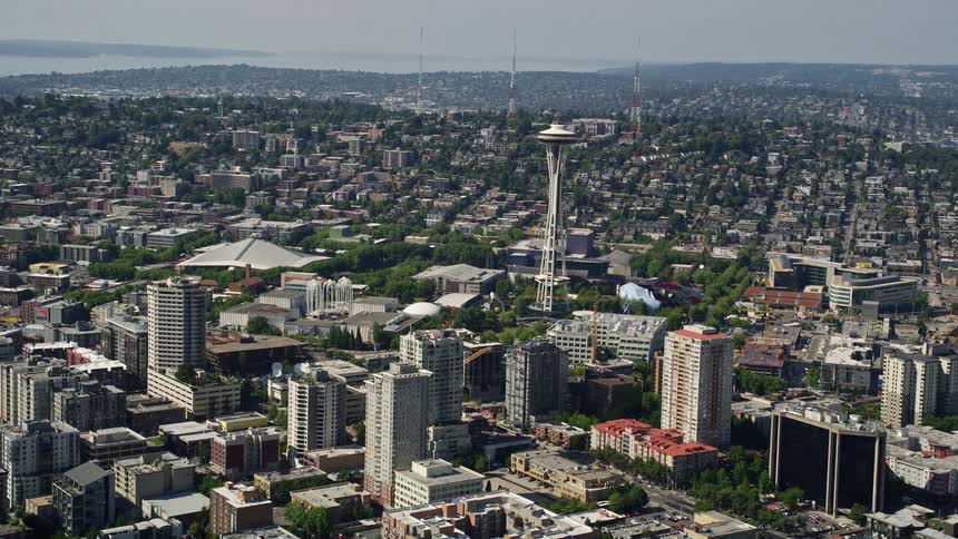 Aerial footage of the iconic Space Needle towering over downtown Seattle skyscrapers on a sunny day showcasing the vibrant metropolis and famous landmark