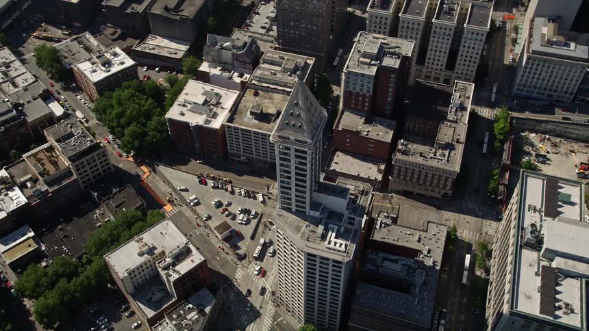  aerial footage of Smith Tower in downtown Seattle Washington as it overlooks the bustling city and the traffic on the streets and highways along the coast