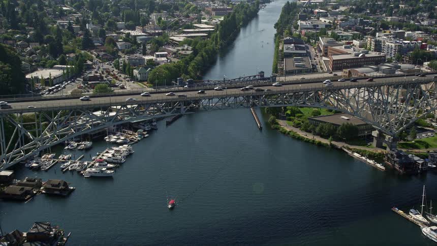 Aerial footage flies over Lake Union and approaches the Aurora Bridge capturing light traffic crossing the span and the scenic surroundings of Seattle Washington