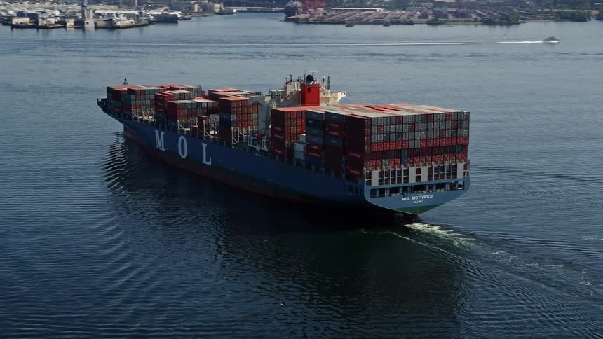 A cargo ship sails through Elliott Bay in Seattle Washington as it moves towards a loading dock leaving a wake behind