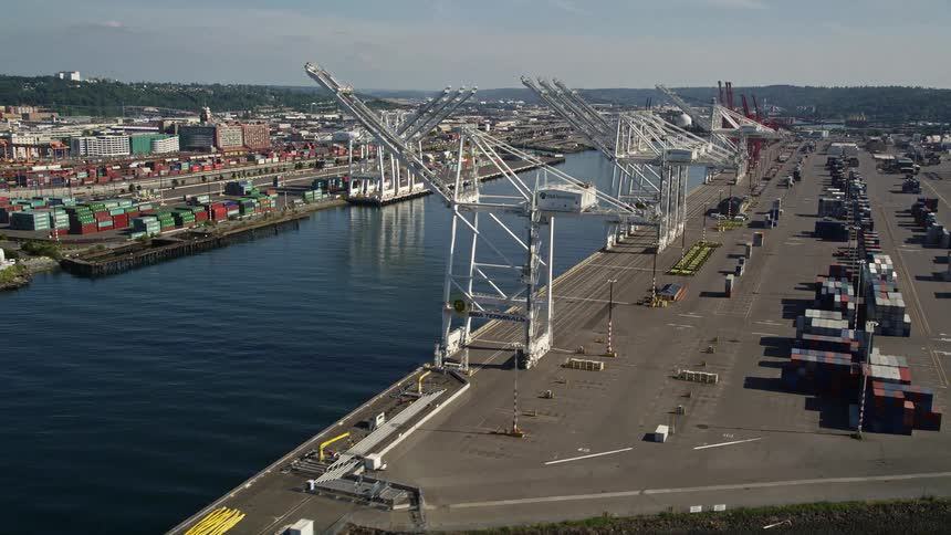 Aerial footage showcasing cargo cranes lining the waterway at Harbor Island Seattle Washington with a bustling maritime industry in operation during the daytime