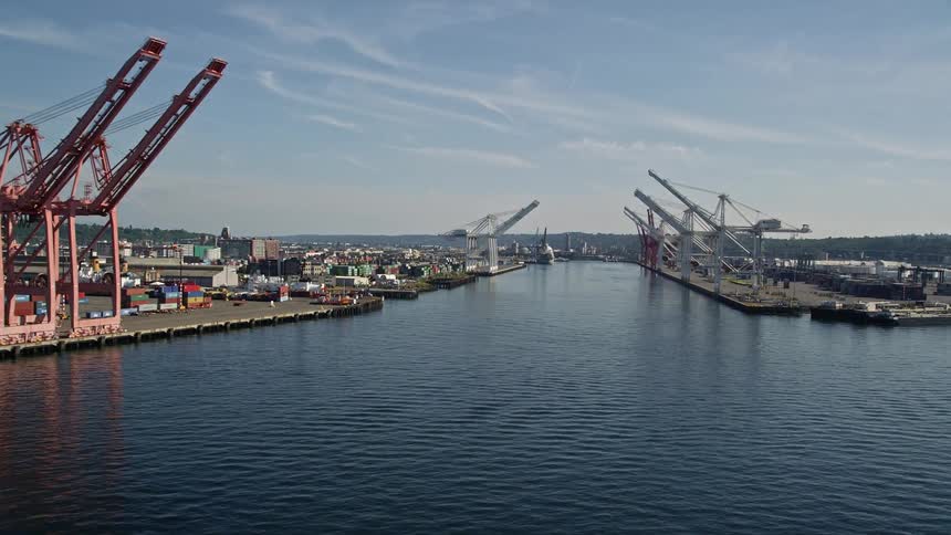 Aerial footage of cargo cranes lining the waterway at Harbor Island Seattle Washington with a view of the bustling industrial port