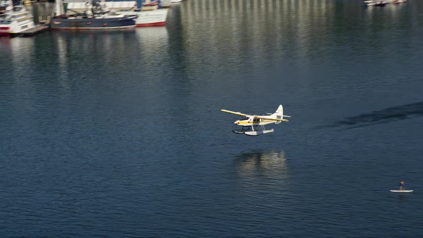 Tracking shot of a seaplane taking off from Lake Union showcasing the beauty of the blue water and the cityscape of Seattle Washington