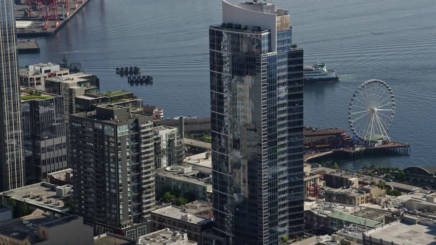 A ferryboat approaches the Central Waterfront amidst skyscrapers in Downtown Seattle on a sunny day