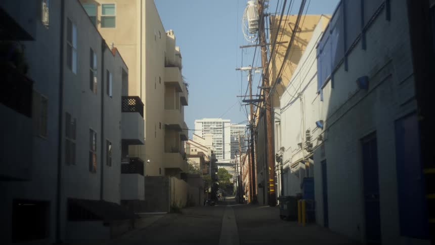 A car drives past a downtown alley between apartment buildings