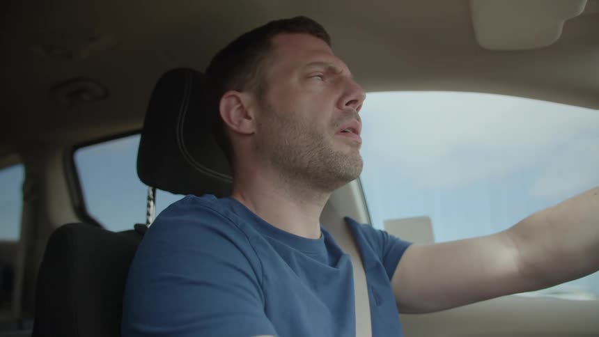 A man is driving his car during the day time