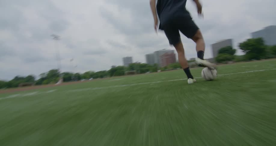 A man playing foot ball on a field alone