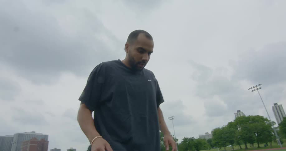 Man bounces a soccer ball alone on a field in the city