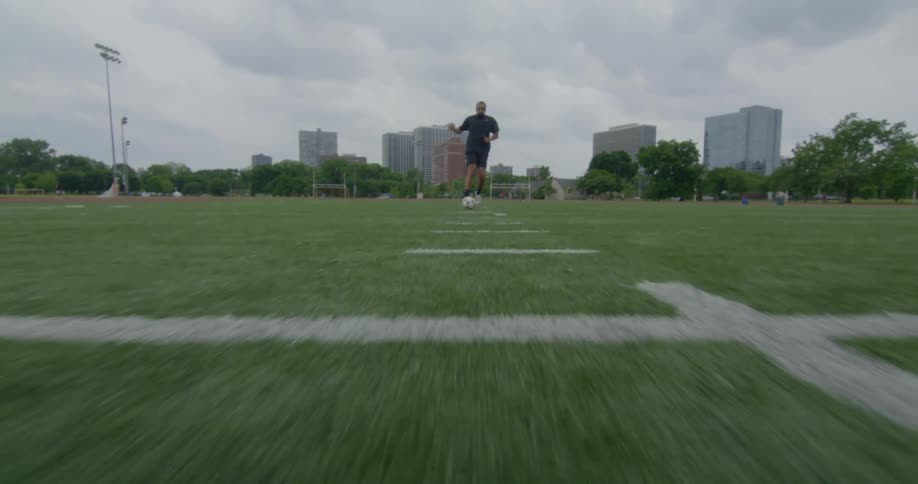 A man kicks a soccer ball down the field