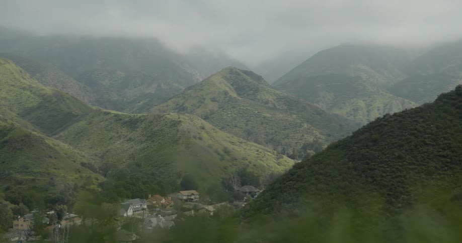 A rural town hidden in a valley between lush verdant mountains