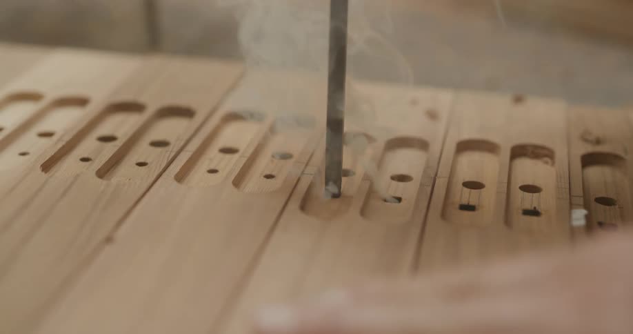 A man uses a hot metal rod to create holes in wood