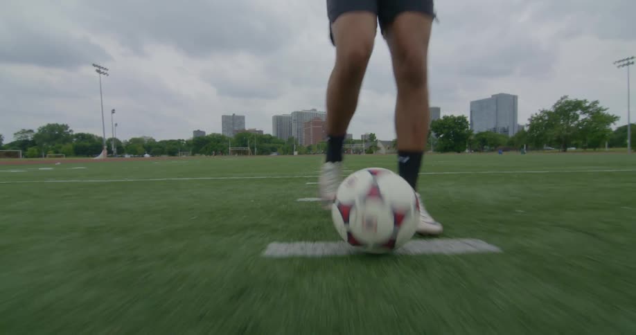 A man is playing soccer in a field by himself