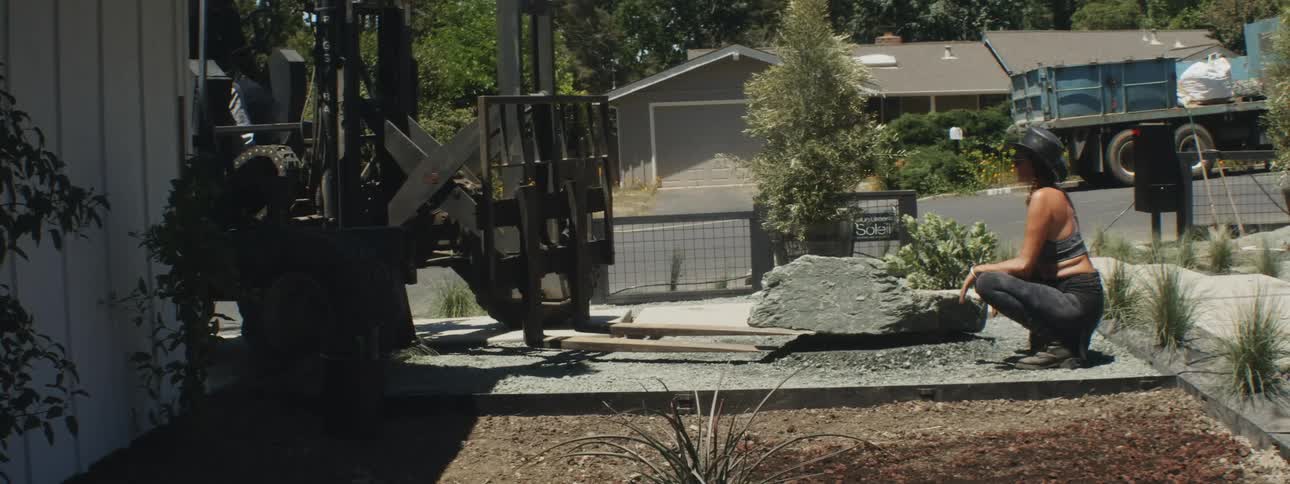 A woman looking at a forklift outdoors