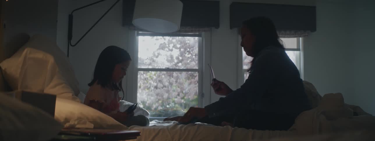 Mother and daughter play cards on bed in bedroom
