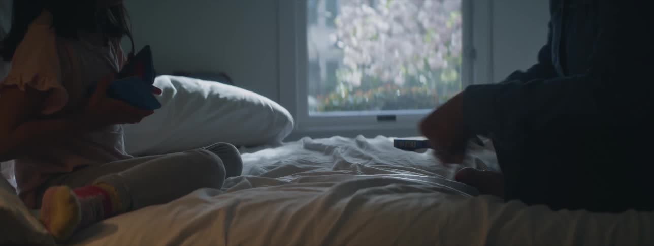 A little girl on her bed shuffling a deck of cards to play with an adult