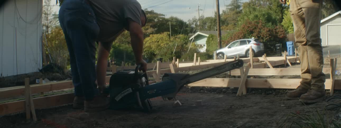 A man diligently tends to his yard focused on operating a small machine as he carries out maintenance tasks with precision and care creating a wellmaintained and inviting outdoor space