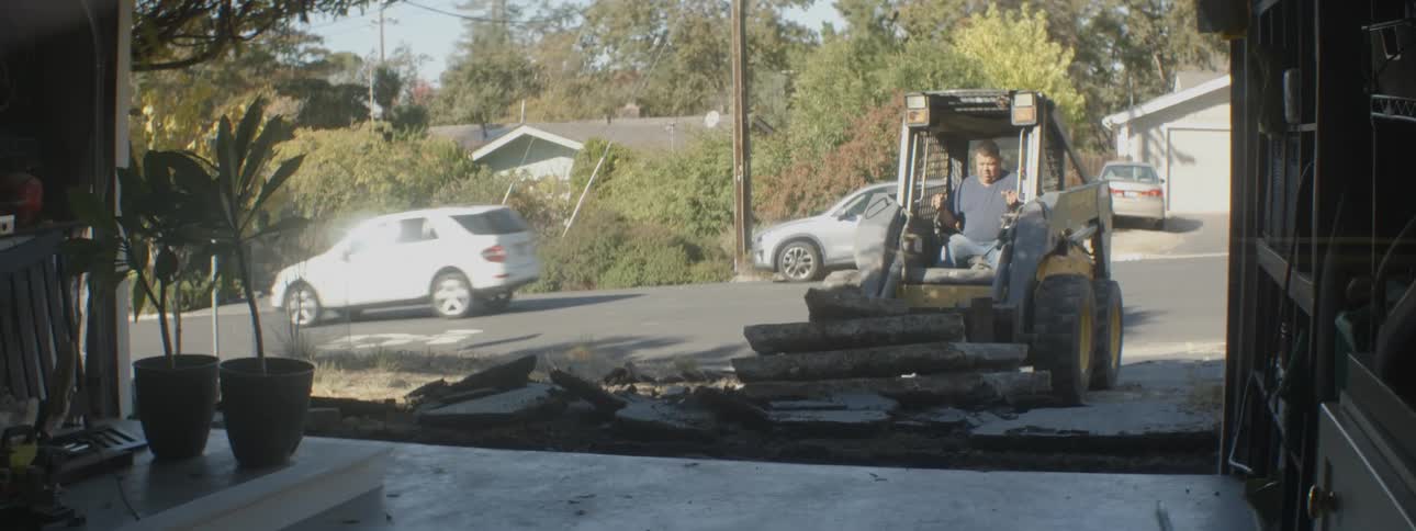 Man operates forklift to move slabs from between open garage and street