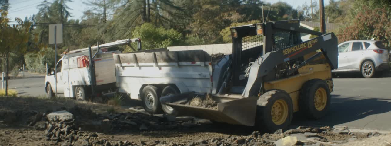 A man uses a bulldozer to move dirt in a parking lot