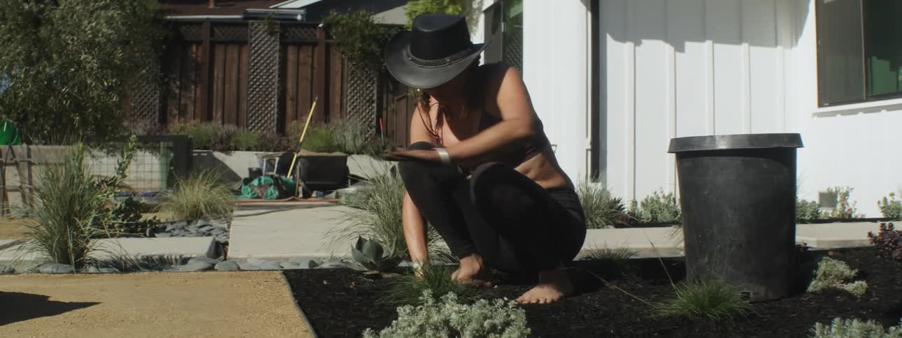 A woman sifts dirt in her backyard garden