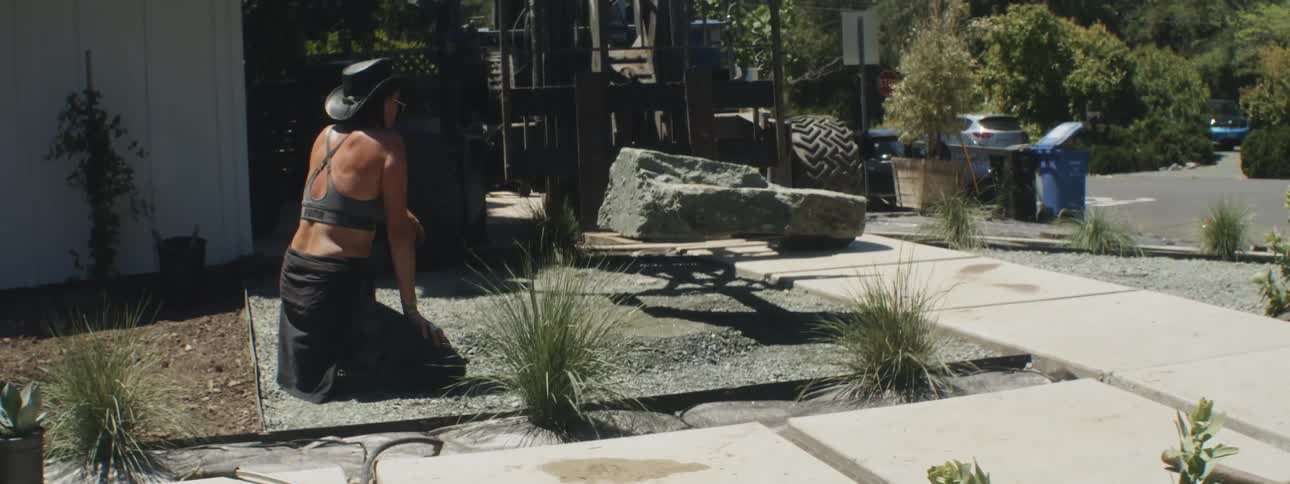 A woman directs a vehicle on where to lower a concrete slab outside a house