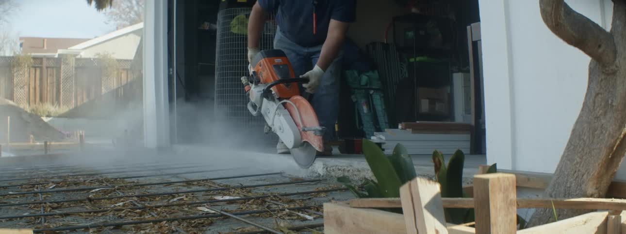Man uses power tool on garage concrete bordering rebar framework