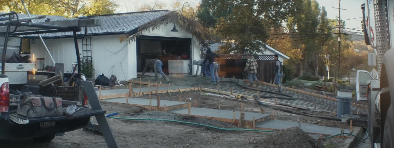 A construction crew works on the driveway of a house