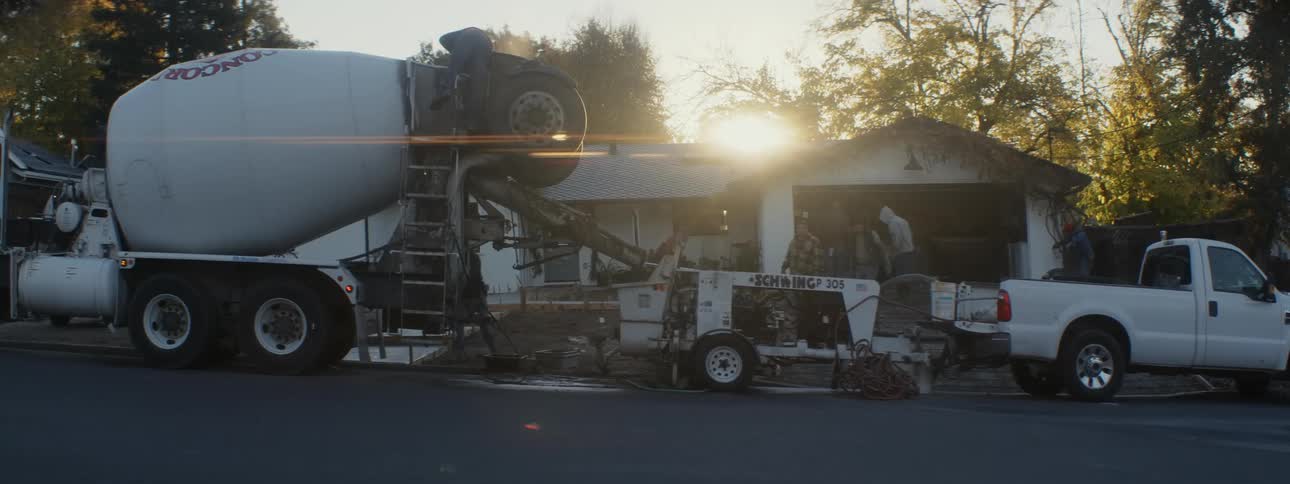 A cement mixer spins outside a house
