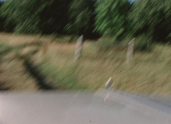 Vintage vehicle driving on a dirt road through the countryside caught on vintage film