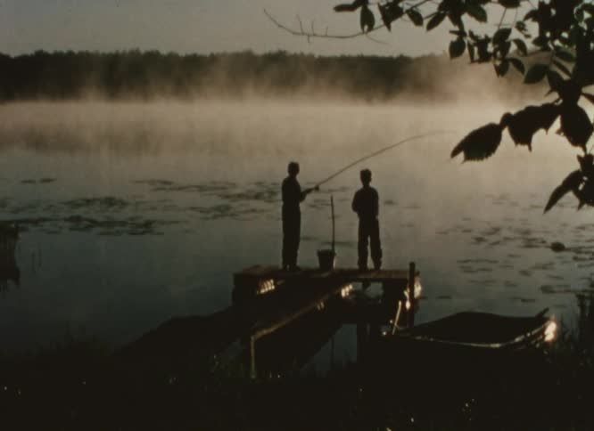 Two boys stand on a dock and fish