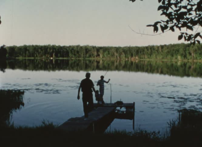 A man walks toward his grandson fishing off a pier