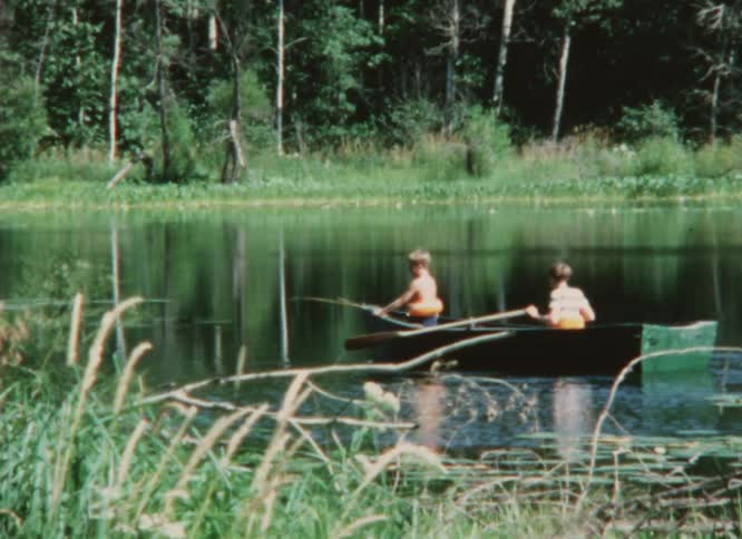 Two boys rowing on a boat on a lake caught on vintage film