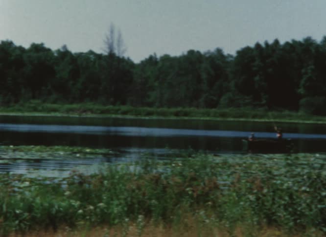 Two boys wave from their boat docked in the river