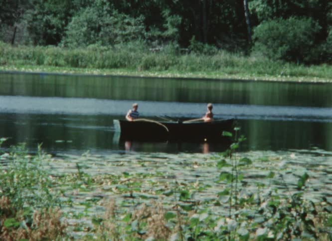 Two young men fish in a boat in a lake