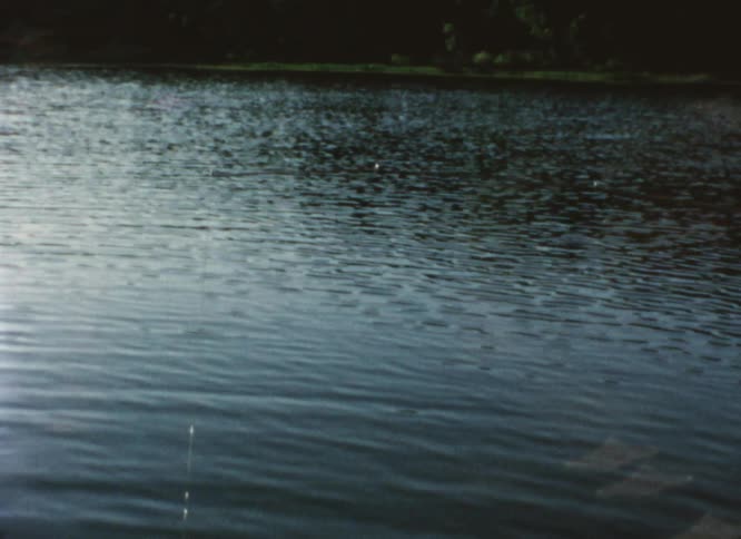 Sunlight reflects on the water as it ripples and waves and there is a fishing pole hanging over the water