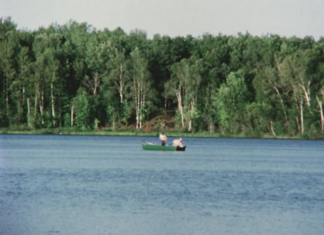 A pair of people aboard a boat on a waterway during the day