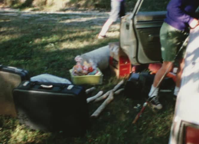 A man is unpacking his car in the yard
