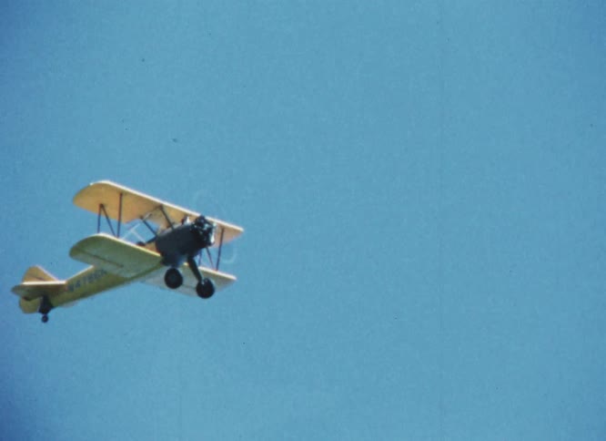 Biplane flying on a clear blue sky caught on vintage film