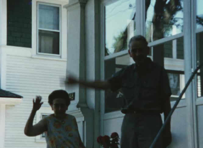 Elderly couple waves their hands at the camera caught on vintage film