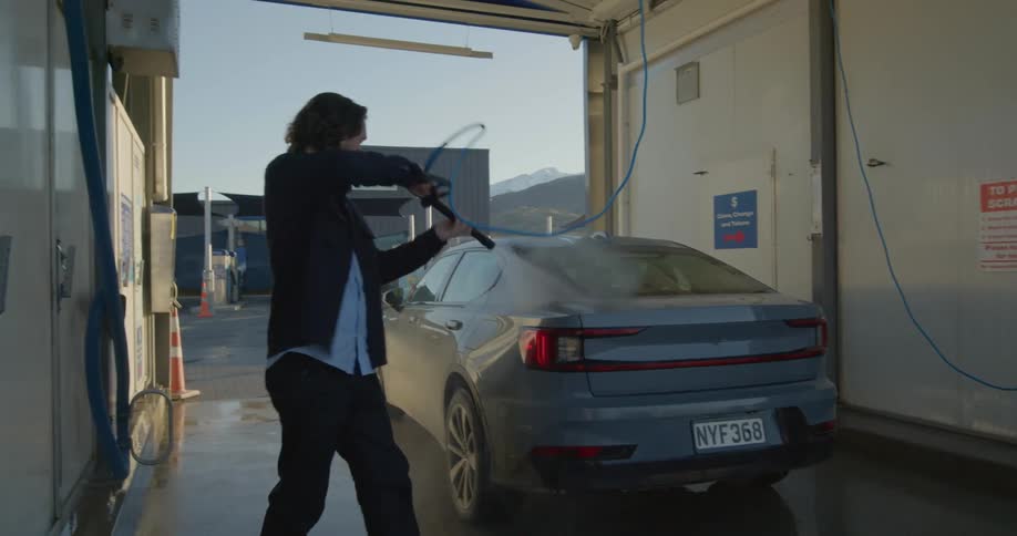 A man walks around while power washing his vehicle at a selfservice car wash
