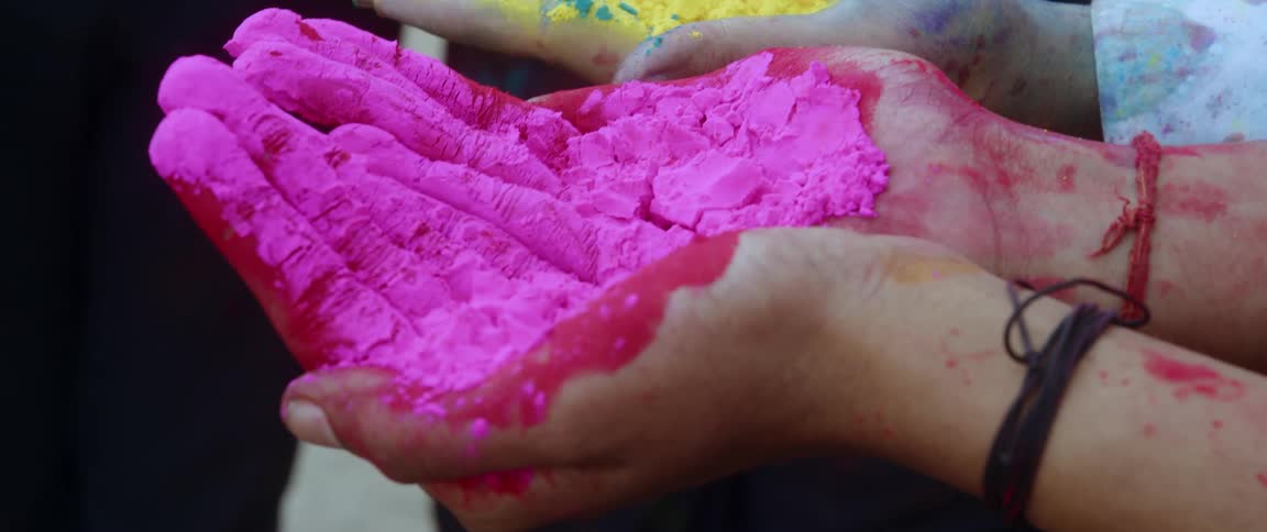 Three pairs of hands holding three types of colored powder