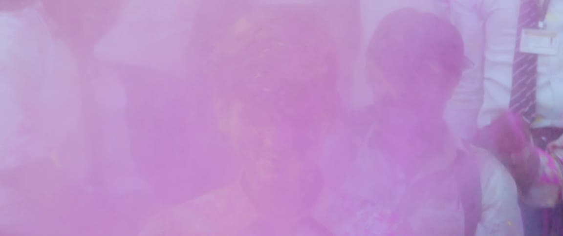 Friends smile while throwing colored powder at a man during holi