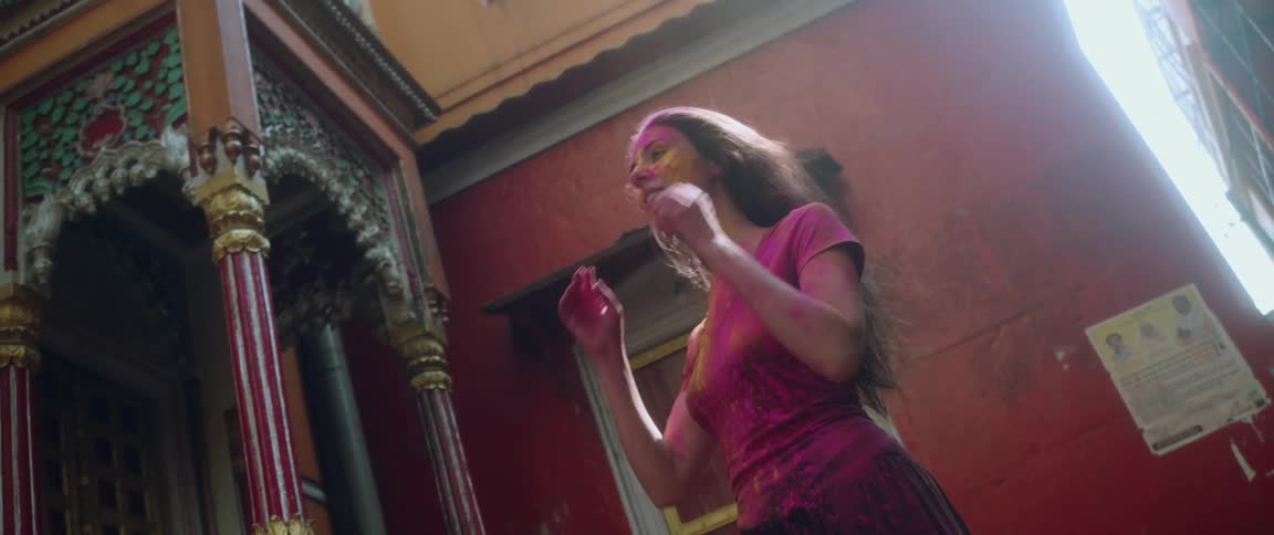 A woman with powdered dye on her face hair and tshirt throws back her hair shaking some powder off