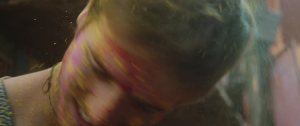 A teenage boy with dye all over himself shakes his head so the dye falls out of his hair