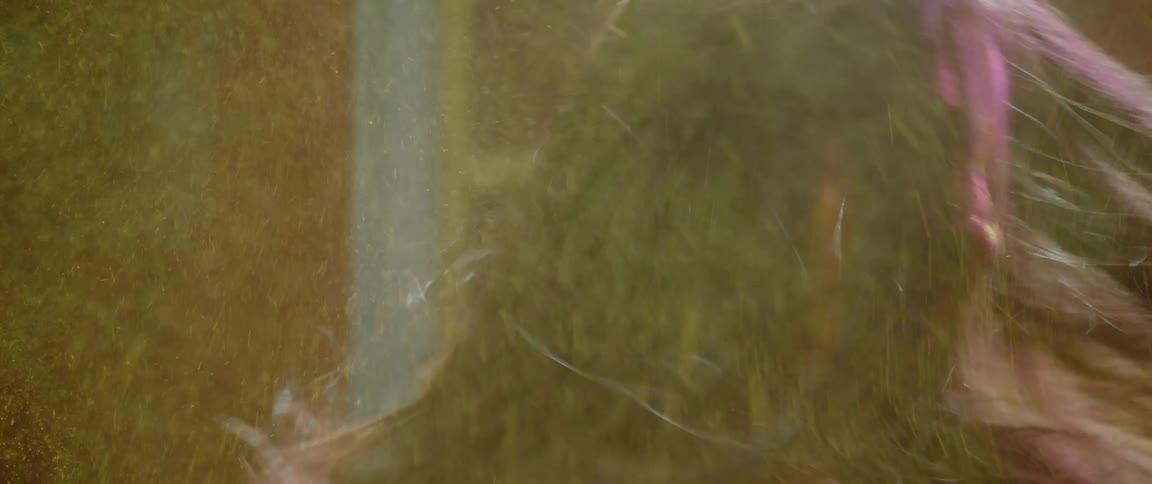 Close up of the face of a woman covered in colored dust shaking her hair