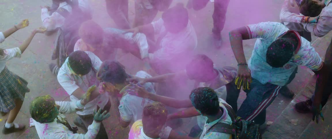 A group celebrates holi by throwing colored powders in the air